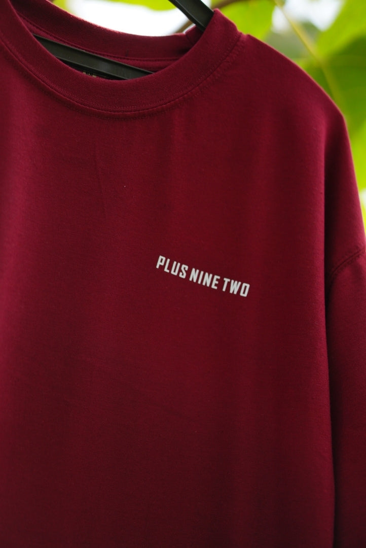 Close-up of Plus Nine Two logo on Ajrak Maroon Essentials Dropshirt men’s oversized t-shirt