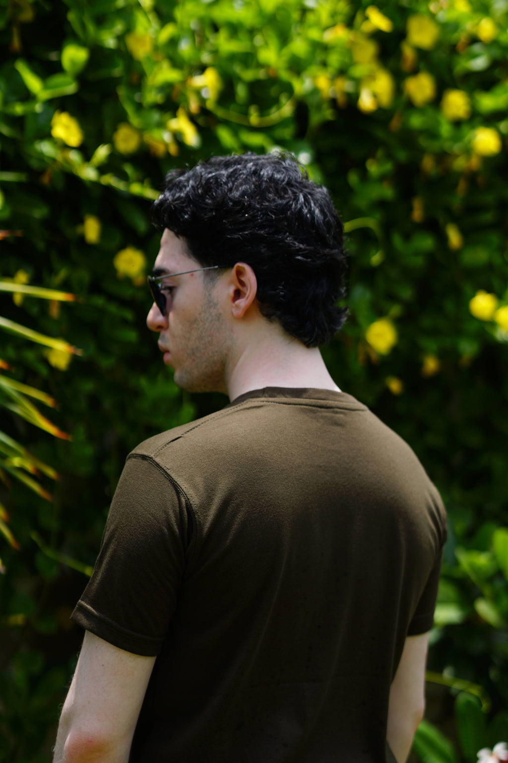 Back view of Men’s Army Green Essentials Blend T-Shirt in outdoor greenery