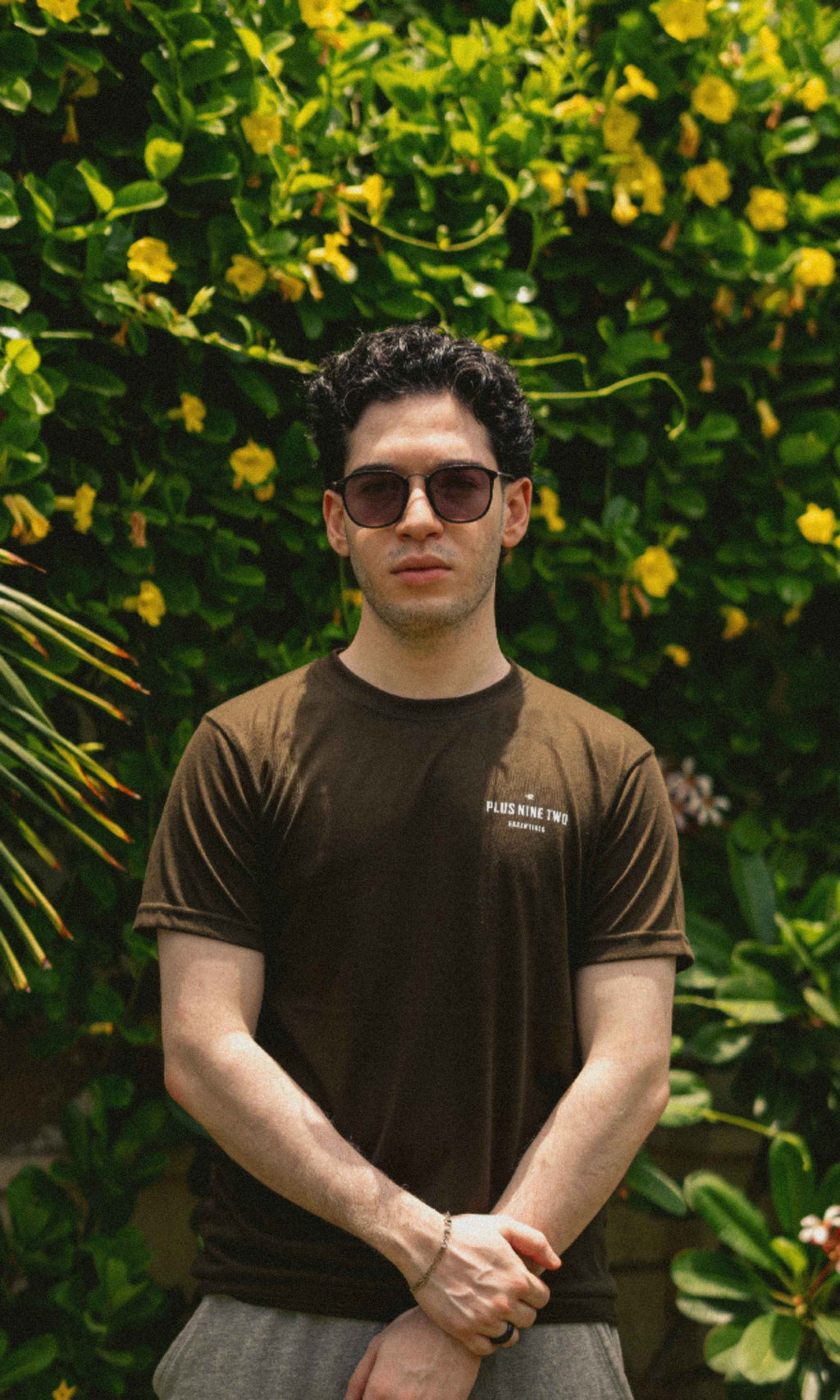 Male model wearing Army Green Essentials Blend T-Shirt in a garden photoshoot