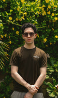Male model wearing Army Green Essentials Blend T-Shirt in a garden photoshoot