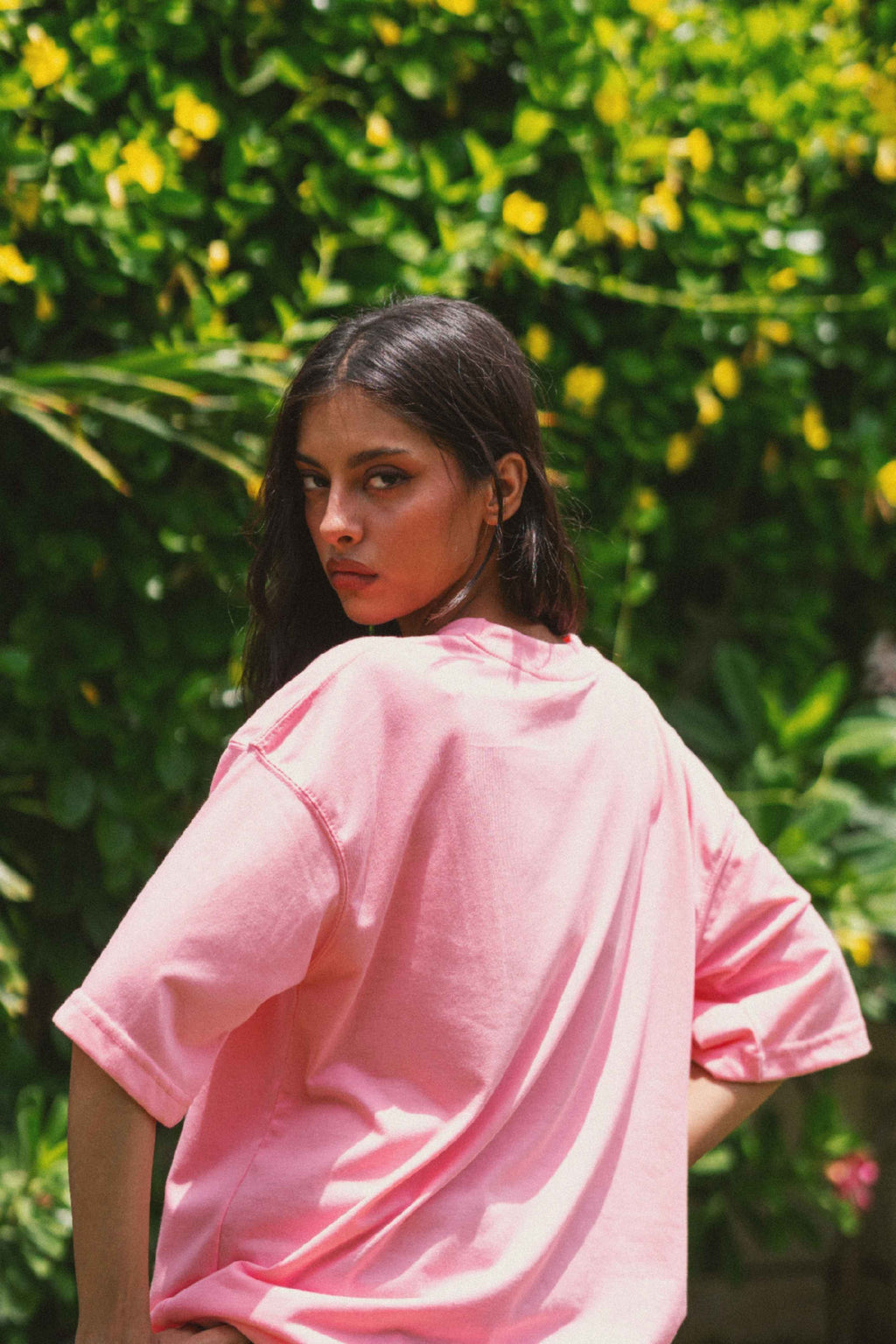 Back view of Women’s Baby Pink Essentials Dropshirt in outdoor greenery