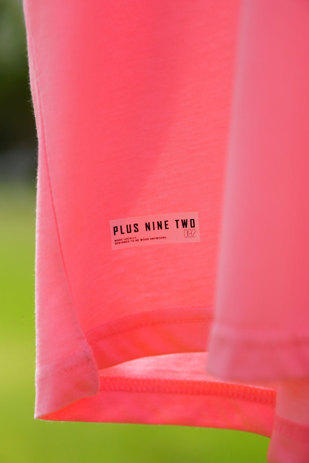Close-up of Baby Pink Essentials Dropshirt hem label detail