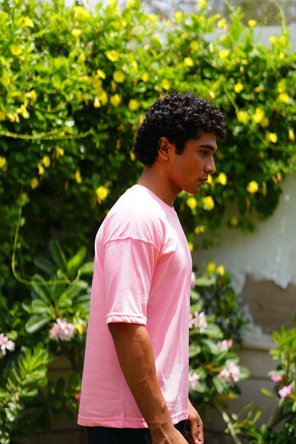 Side profile of male model wearing Baby Pink oversized dropshirt by +92 Clothing