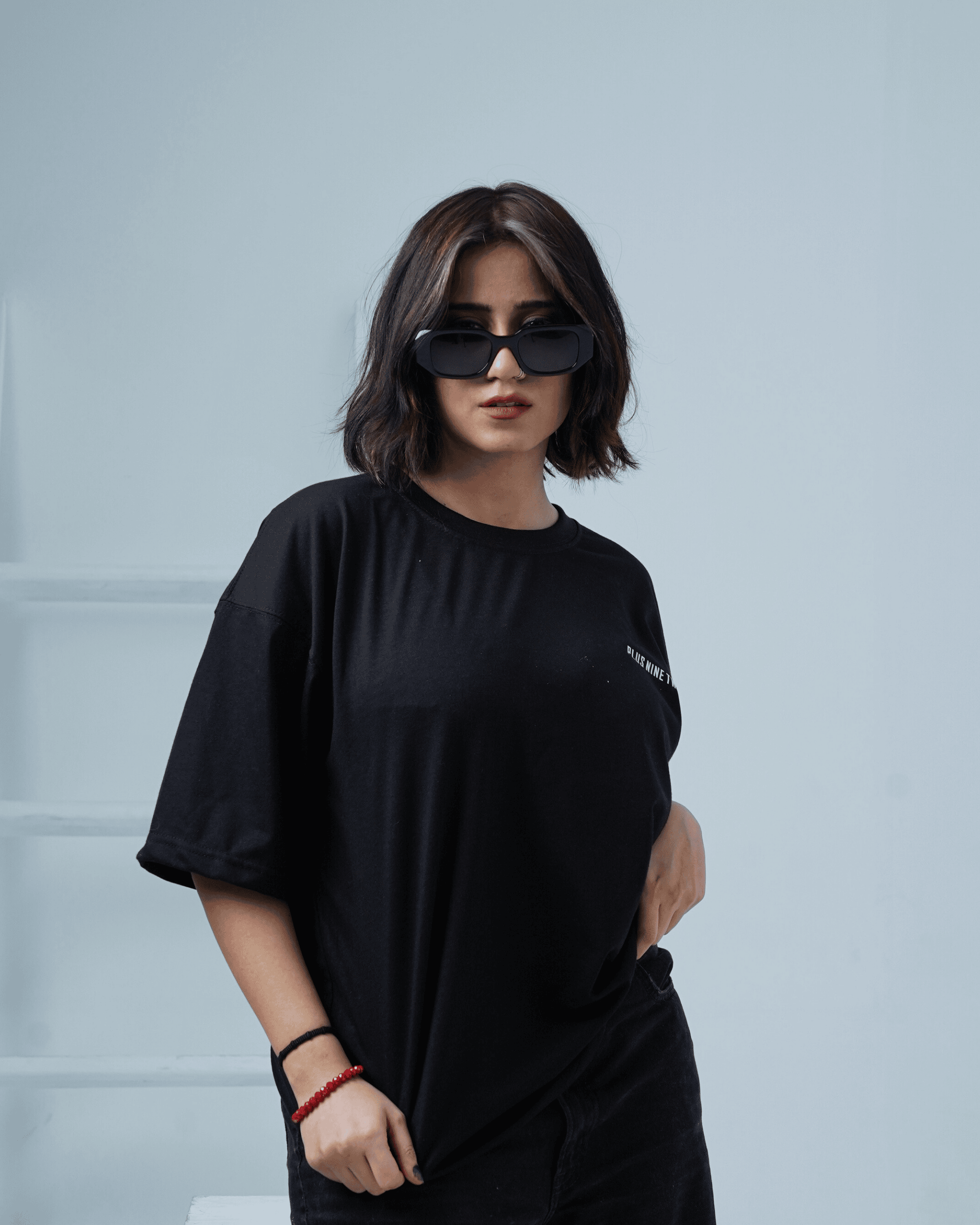 Woman wearing a black oversized t-shirt with text, standing against a light background