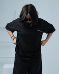 Woman wearing a black t-shirt with text 'PLUS NINE TWO' on a light background