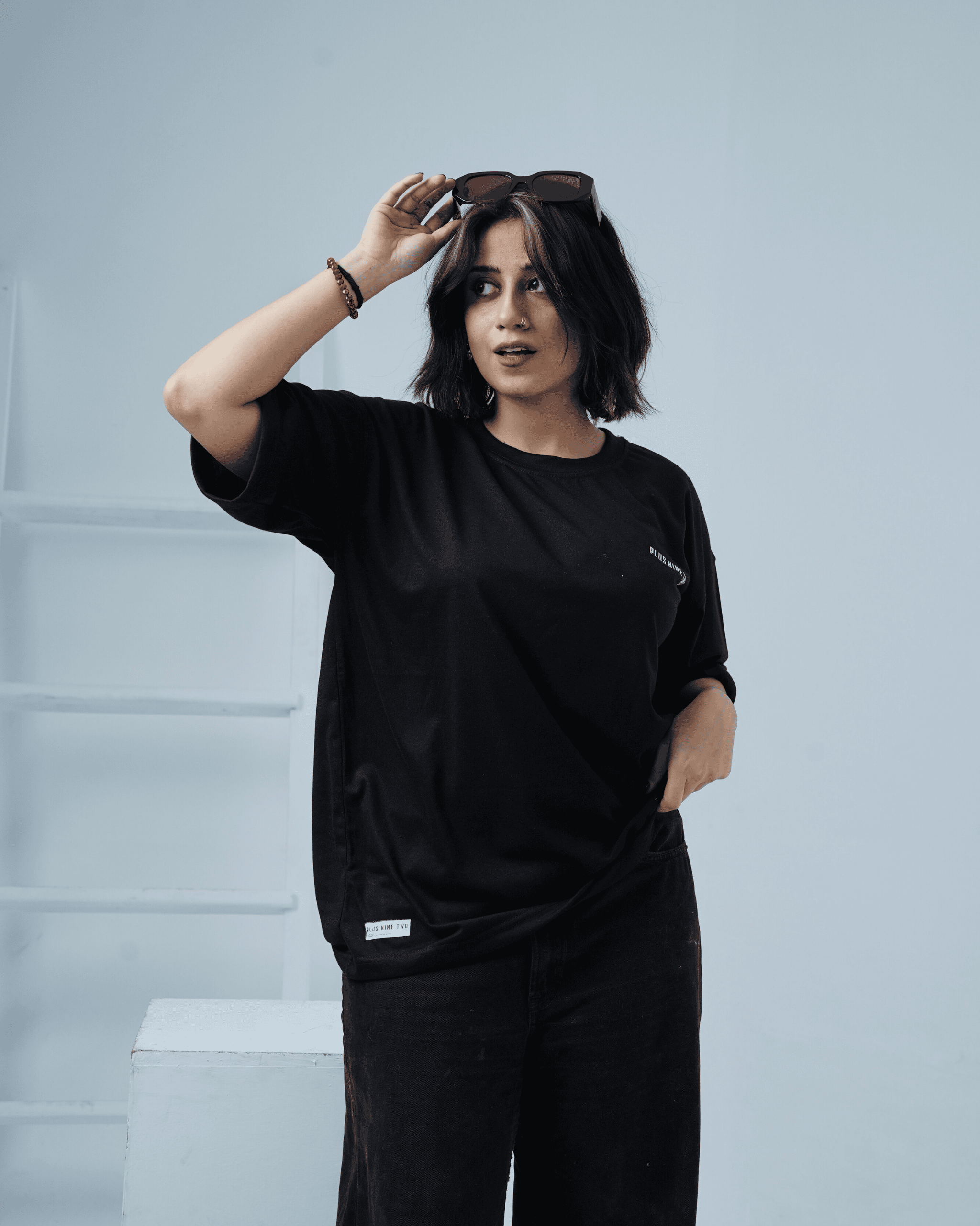 Woman wearing a black oversized t-shirt against a light background