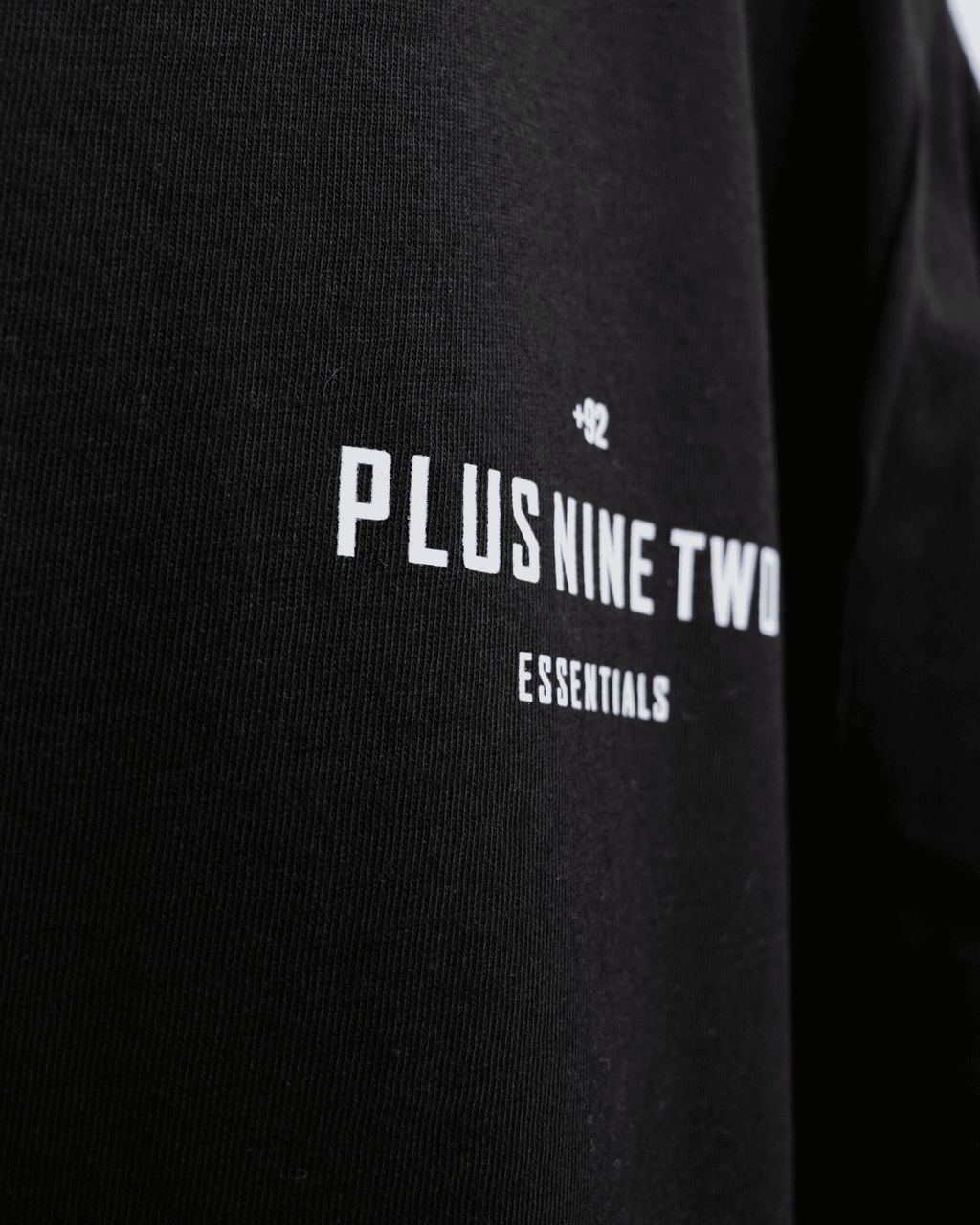 Black t-shirt zoomed into design with '+92' 'PLUS NINE TWO' 'ESSENTIALS' text