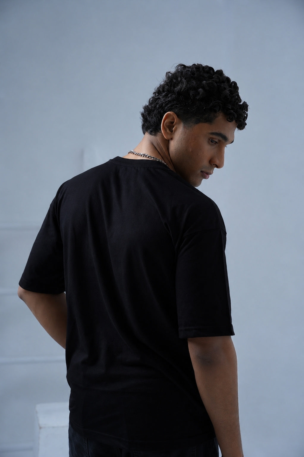 Back view of male model wearing Black Essentials Dropshirt men’s oversized t-shirt by +92 Clothing