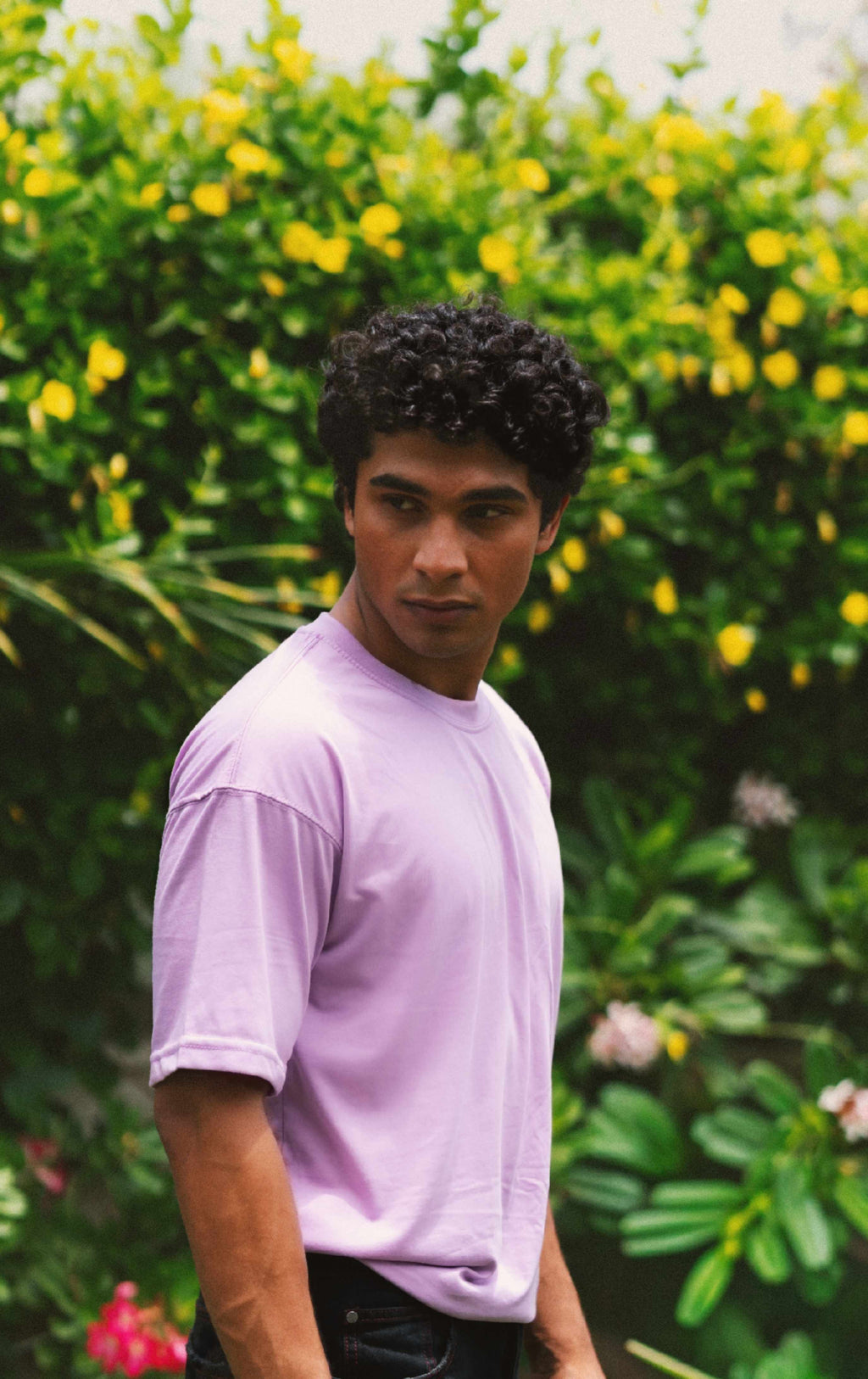 Three-quarter view of a male model looking over his shoulder, showcasing the fit and premium fabric drape of the Lahore Lilac Men's Essentials Drop Shirt.