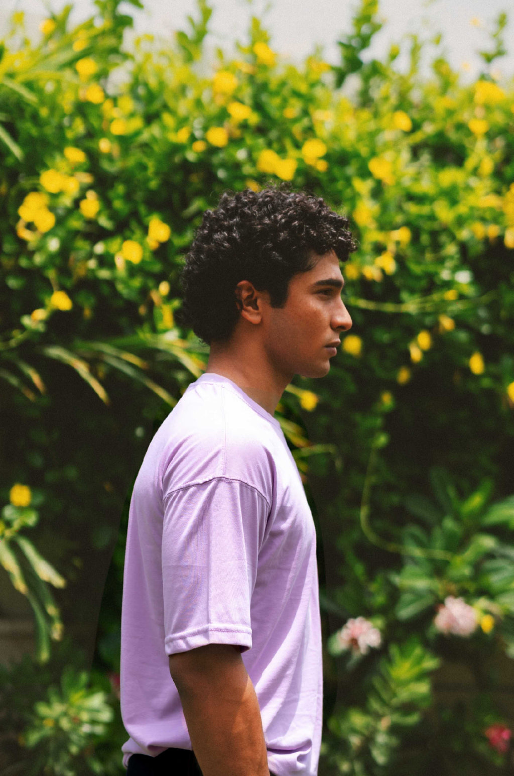 Side profile of a male model modeling the Lahore Lilac Men's Essentials Drop Shirt, showing the relaxed short sleeve length and dropped shoulder design.