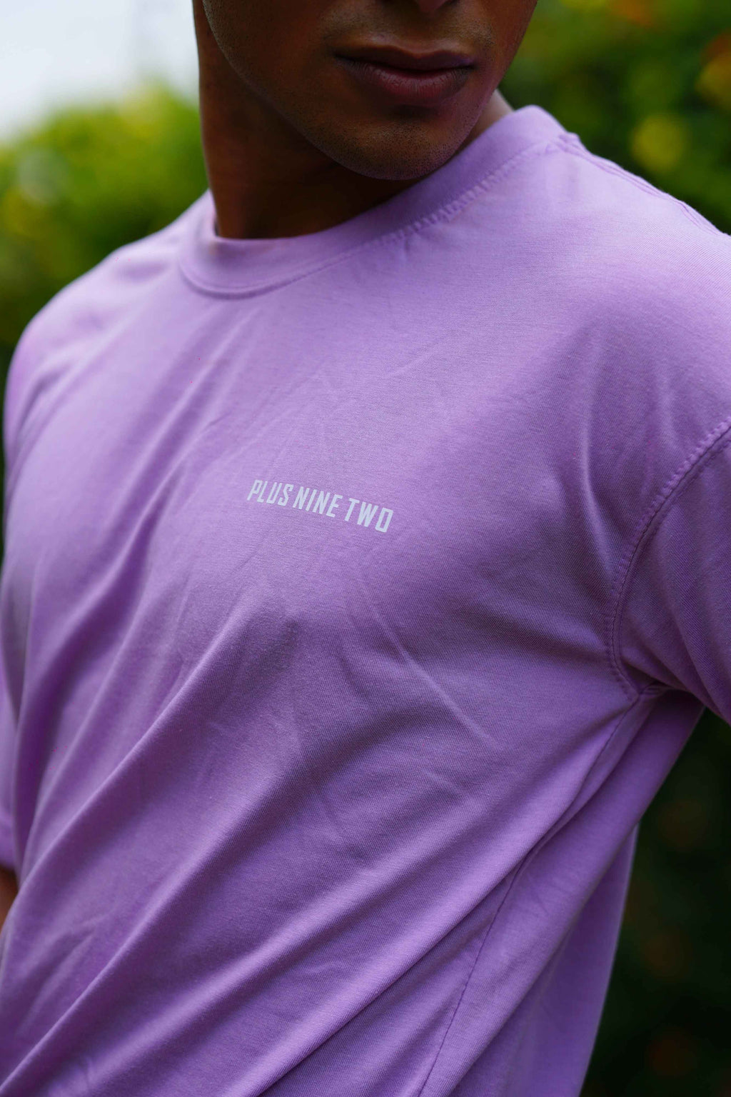 Close-up of a model wearing the Lahore Lilac Men's Essentials Drop Shirt, highlighting the chest area with the white "PLUS NINE TWO" printed text logo.