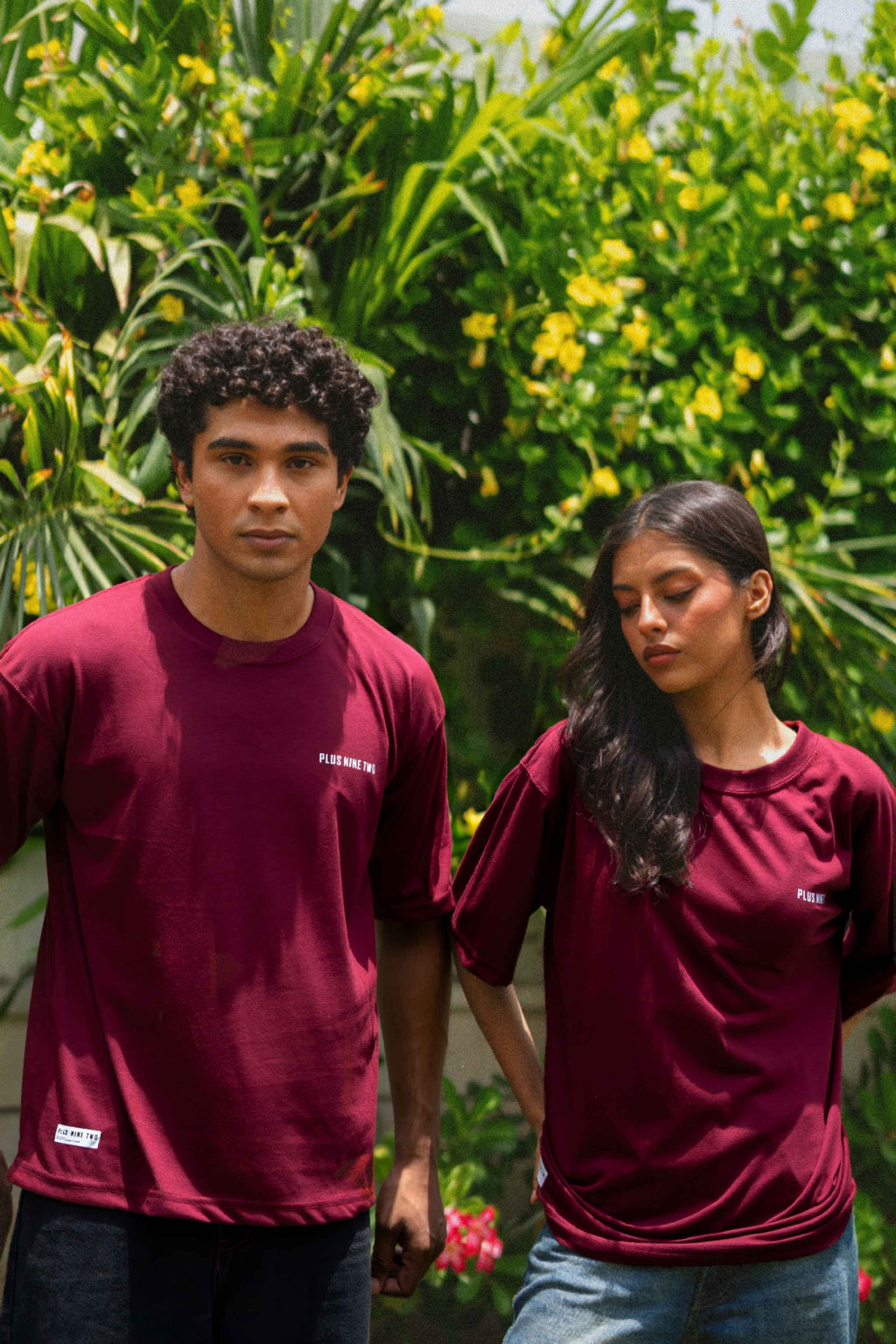 Male and female models posing together outdoors, both styled in the oversized Ajrak Maroon Men's Essentials Drop Shirt.