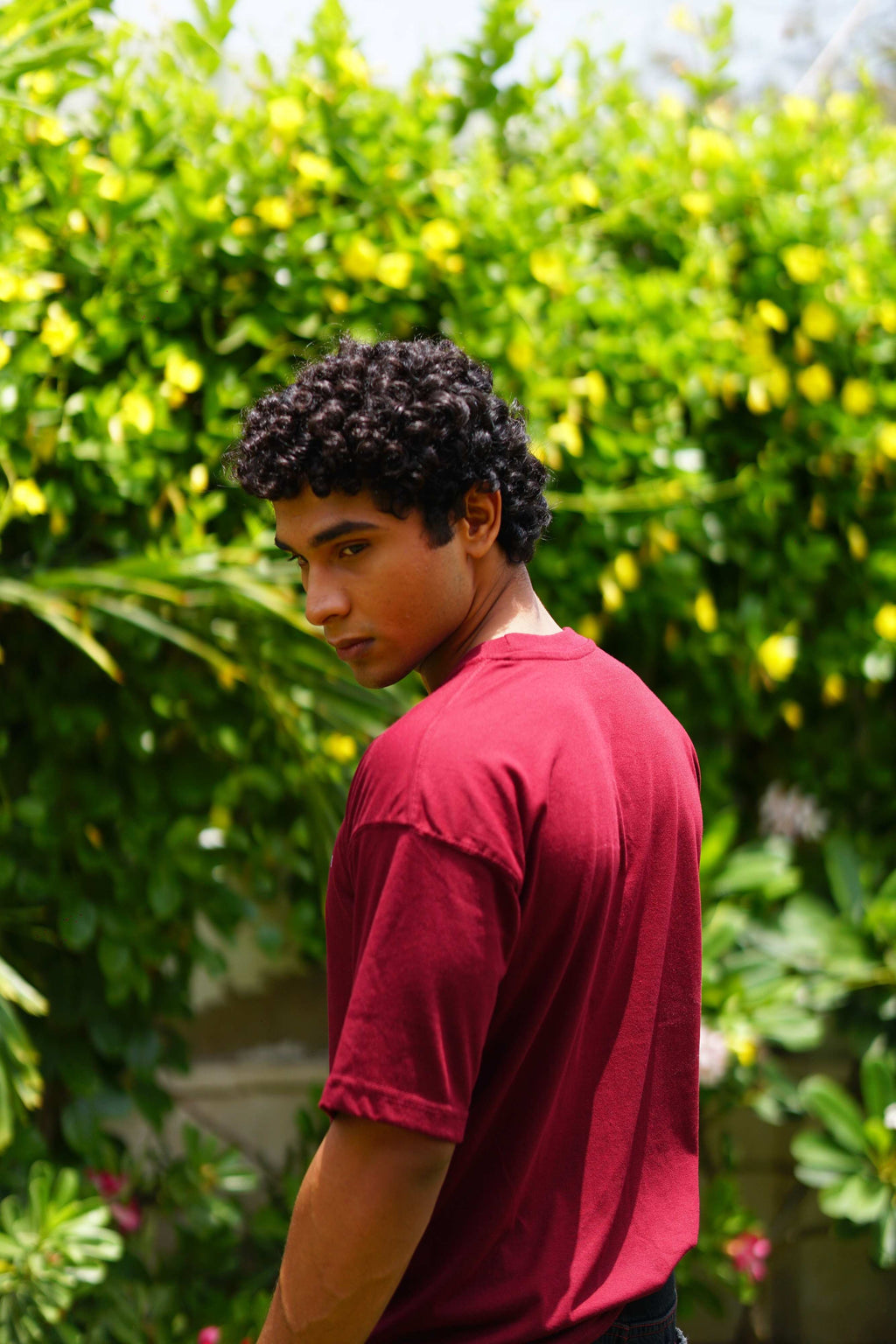 Side profile view of a male model wearing the Ajrak Maroon Men's Essentials Drop Shirt, showing the relaxed short sleeve and dropped shoulder fit.