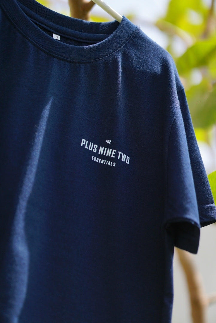 essentials indus navy blue blend t-shirt hanging of a hanger in a garden