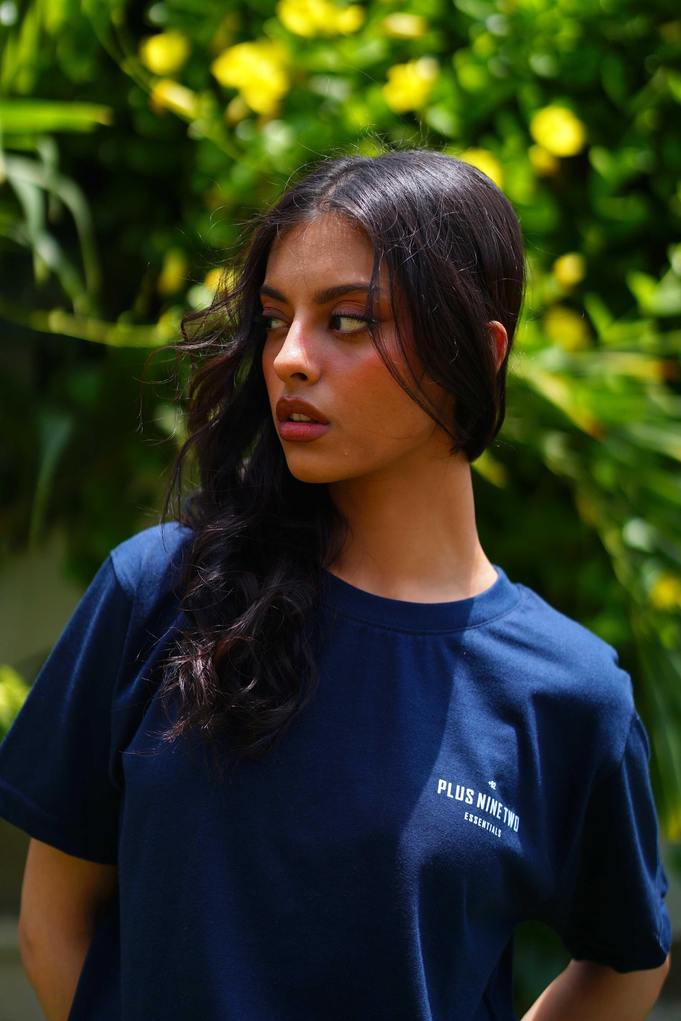 Girl wearing essentials indus navy blue blend t-shirt looking to the right of the camera.