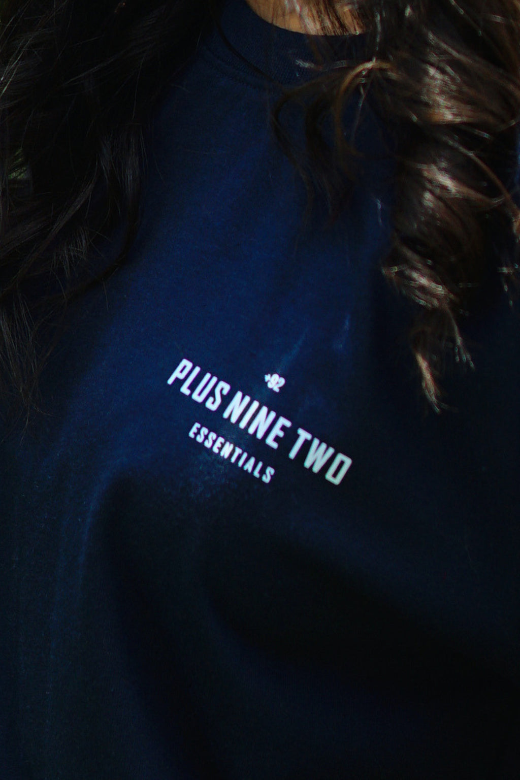 Girl wearing essentials indus navy blue blend t-shirt closeup on pocket print.