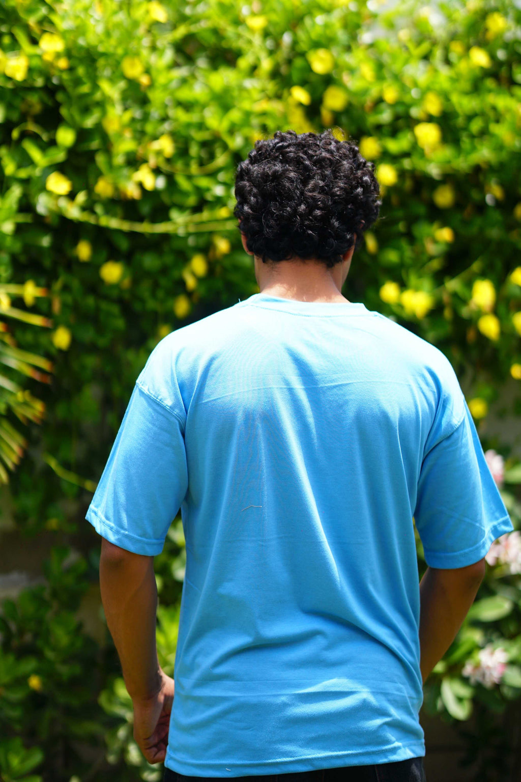 Back view of Men’s K2 Cloud Sky Blue Essentials Dropshirt in garden setting