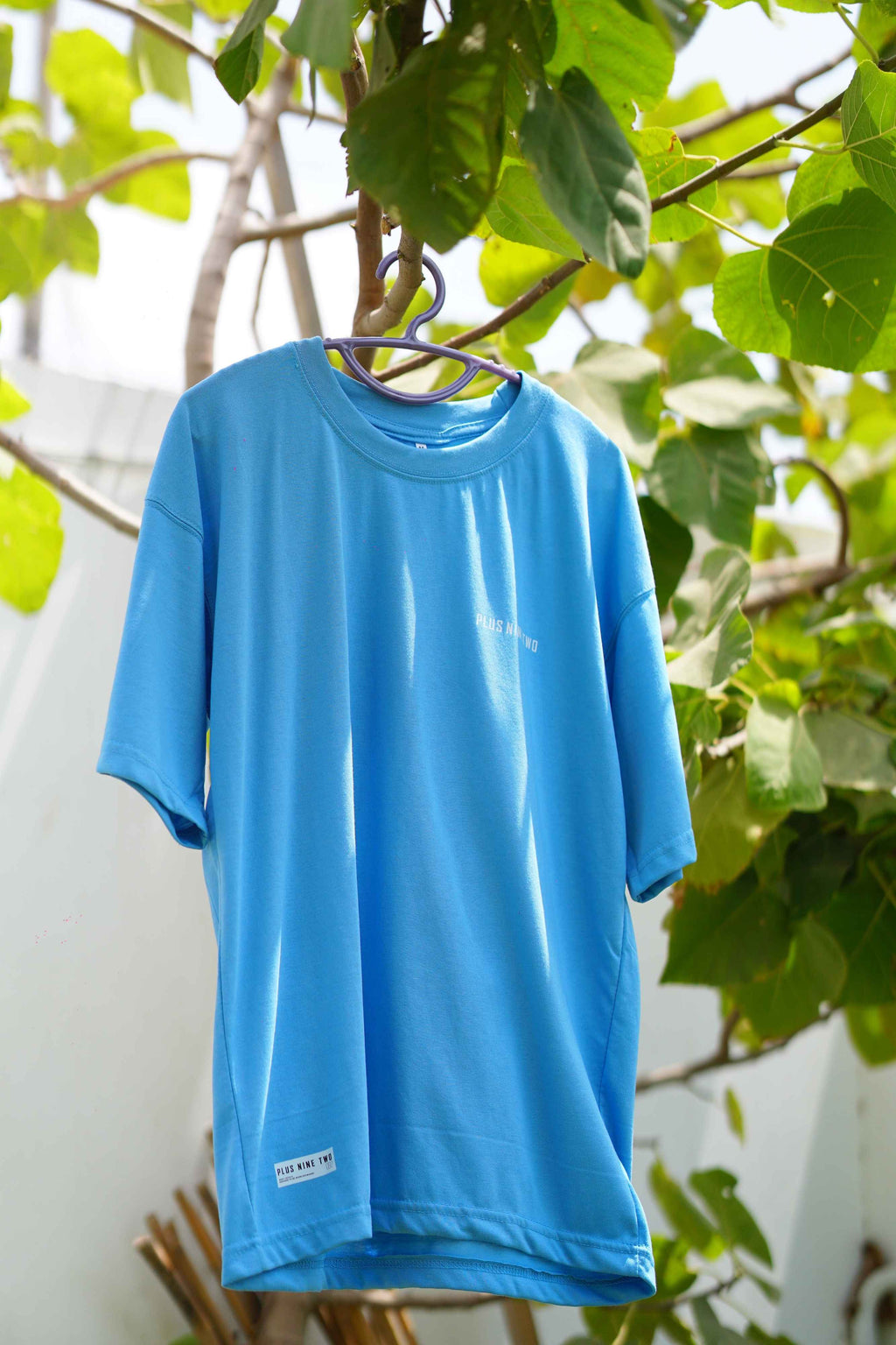 K2 Cloud Sky Blue Essentials Dropshirt hanging on tree branch product photo