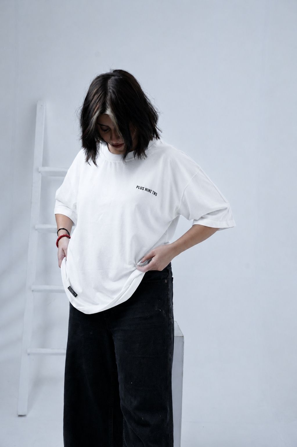 Women posing at 45 degree angle wearing white oversized essentials t-shirt from Plus92 Clothing.