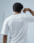 Man wearing an essentials white oversized t-shirt from Plus92 clothing against a light gray background.