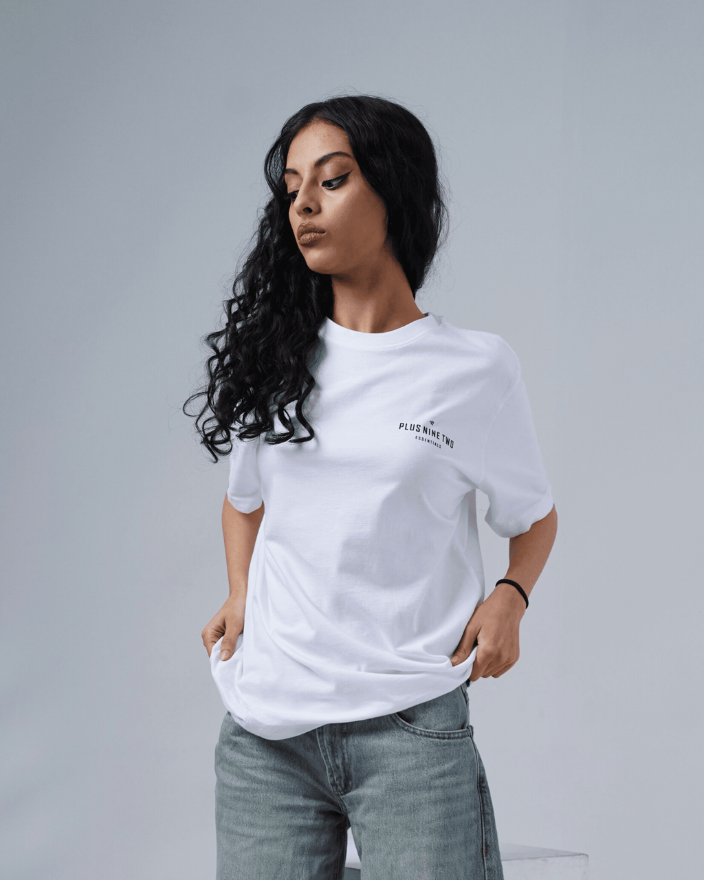 Woman wearing a white t-shirt with a logo on a gray background