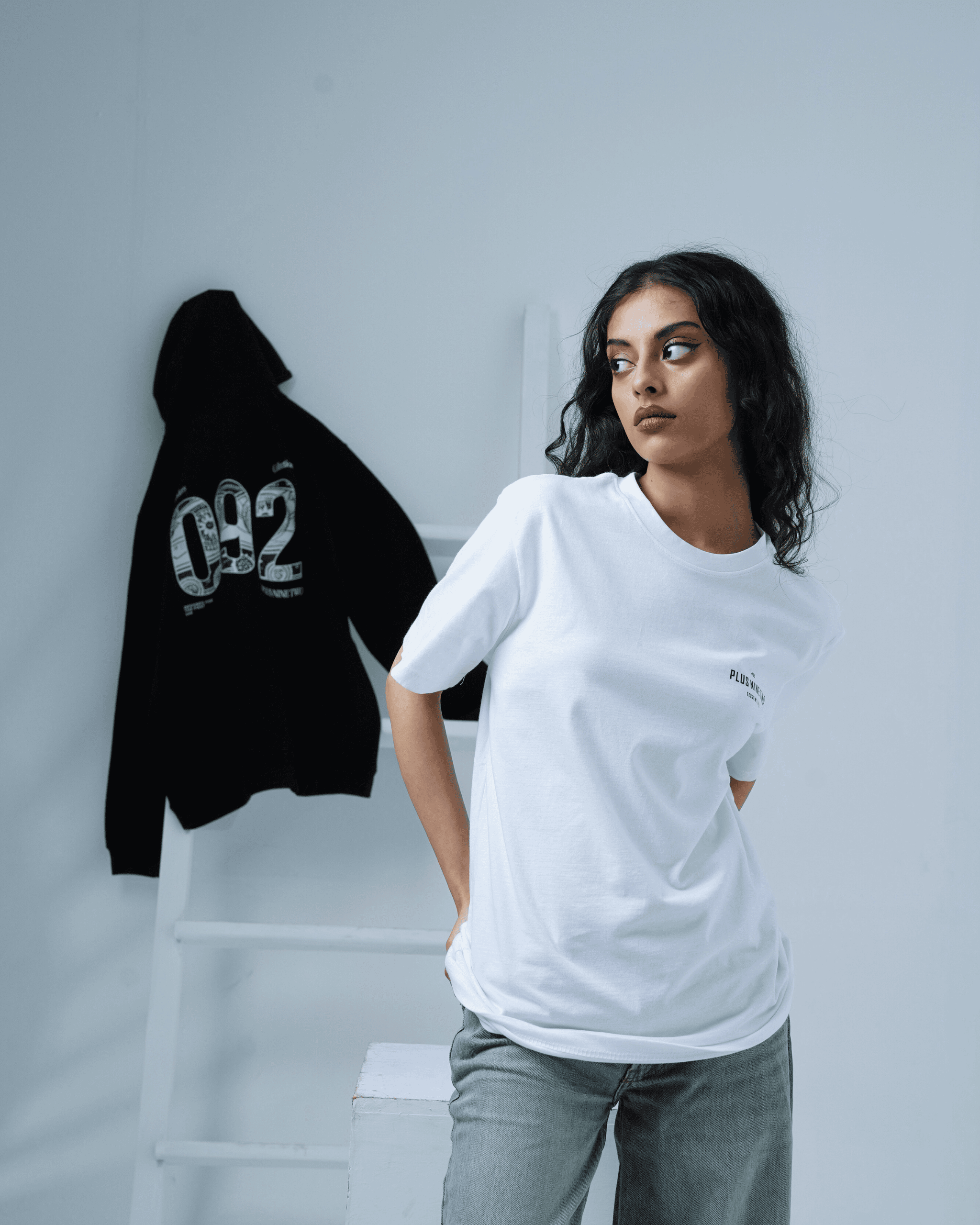 Woman wearing a white t-shirt with a black hoodie on a gray background