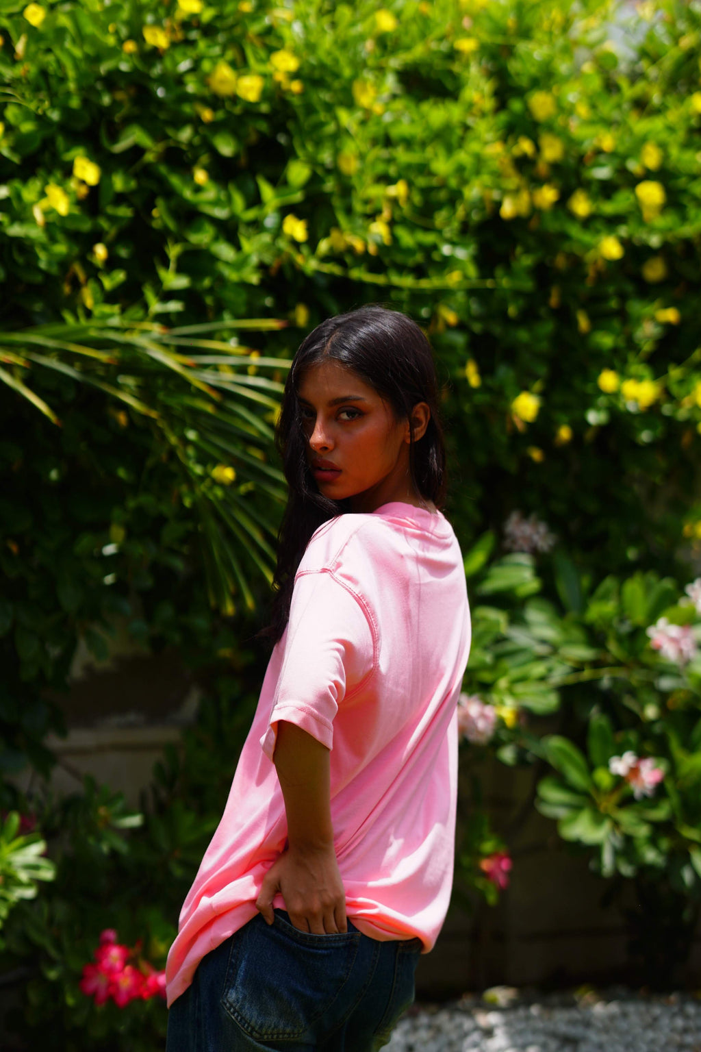 Back view of female model wearing Baby Pink Essentials Dropshirt with relaxed oversized fit