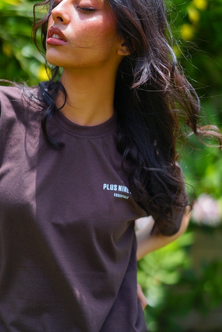 women closeup to t-shirt, standing in garden wearing essentials karak brown blend t-shirt