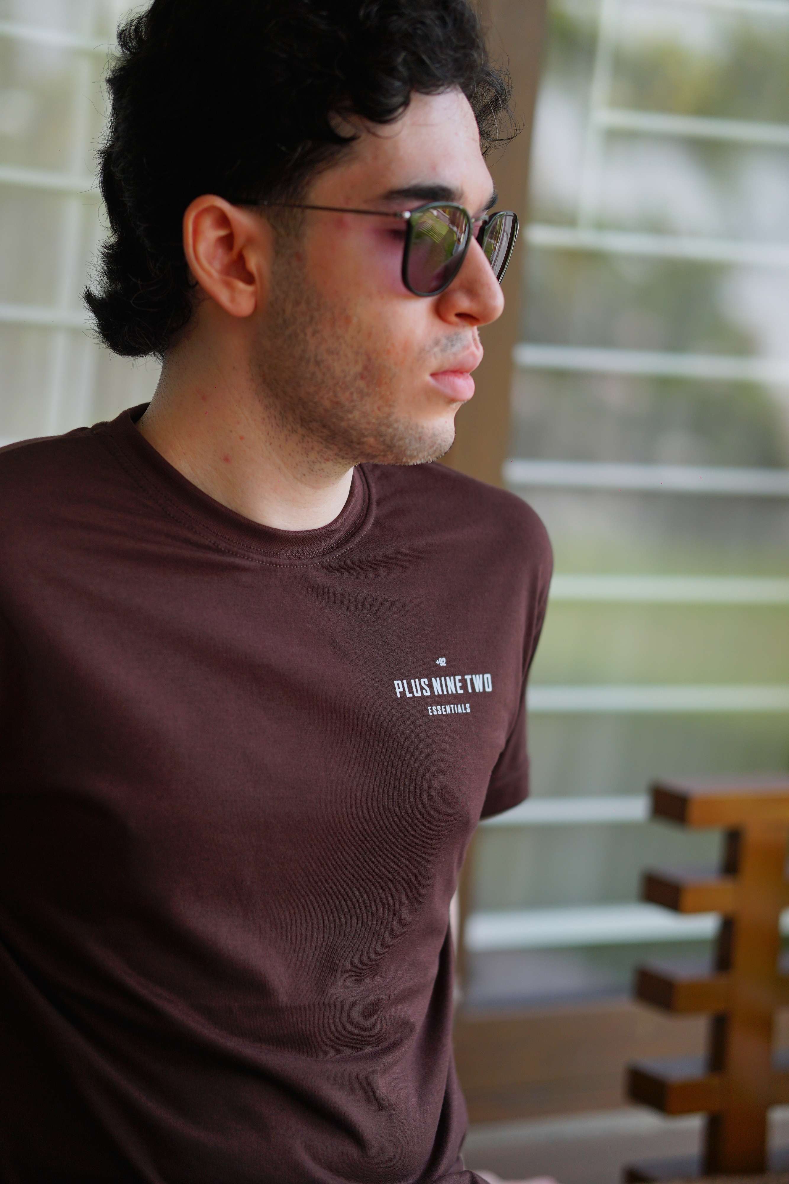 Close-up of man sitting, wearing karak brown men blend t-shirt with pocket print visible