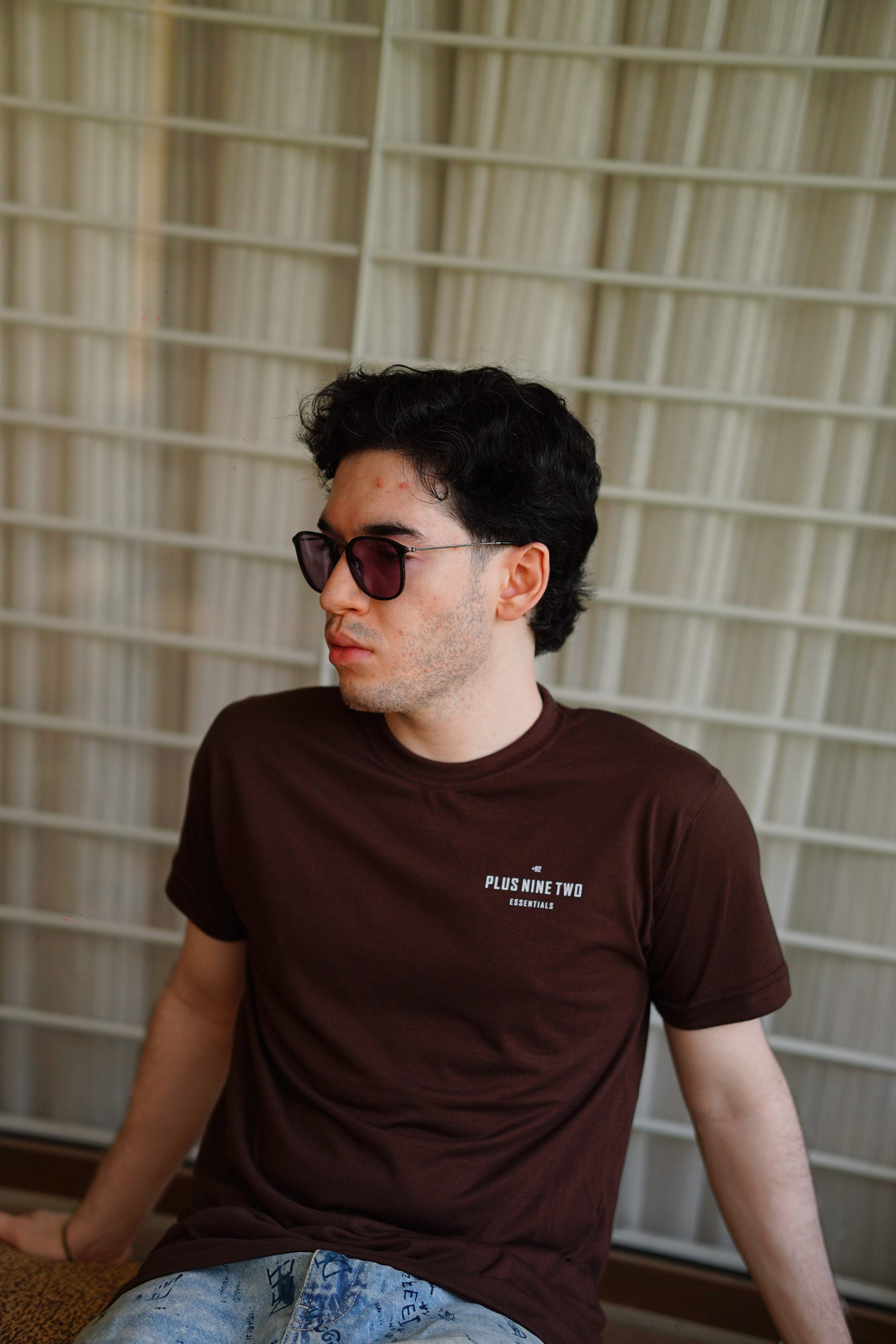 man sitting, wearing essentials karak brown men blend t-shirt with pocket print visible