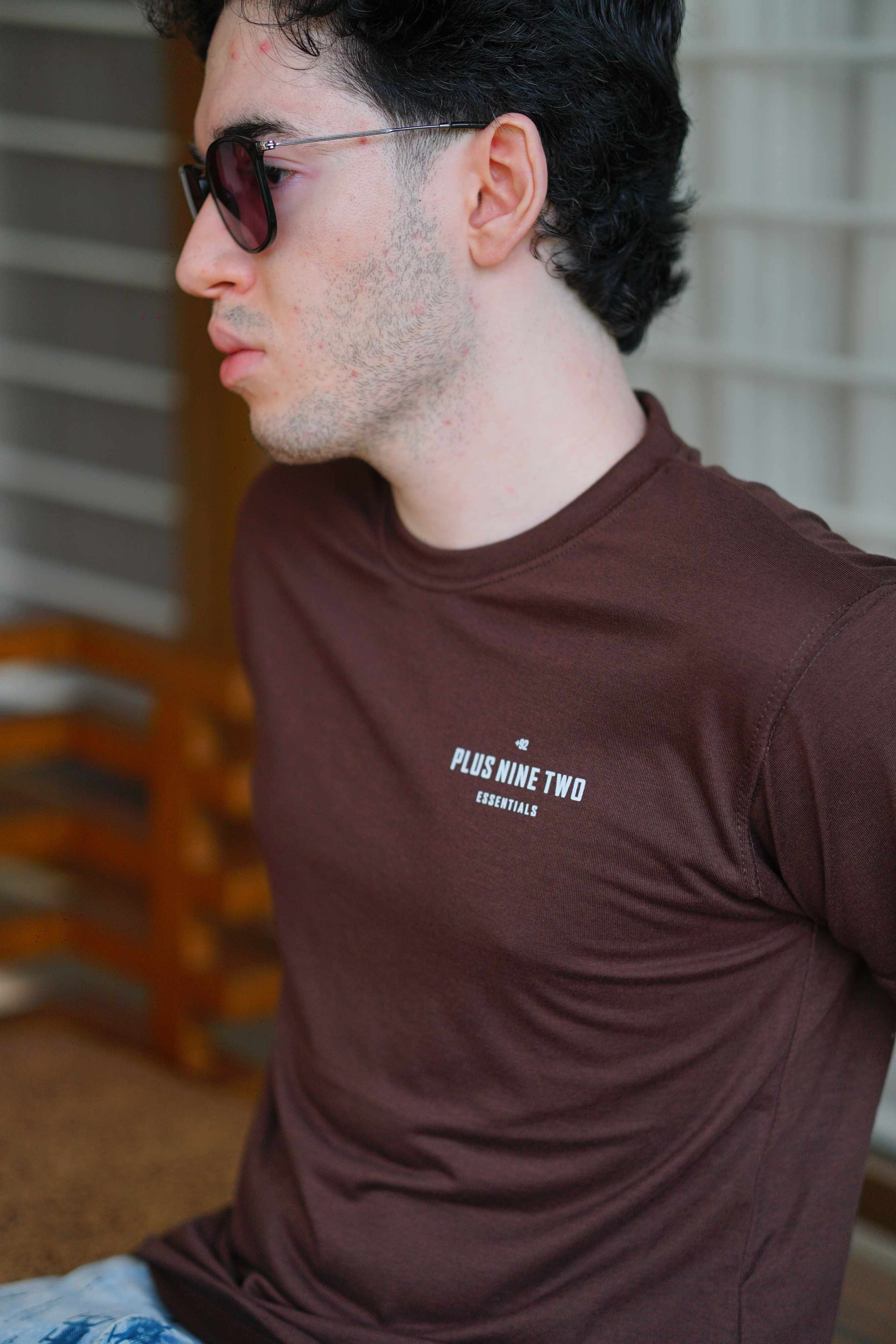 Close-up of man sitting, wearing karak brown men blend t-shirt with pocket print visible